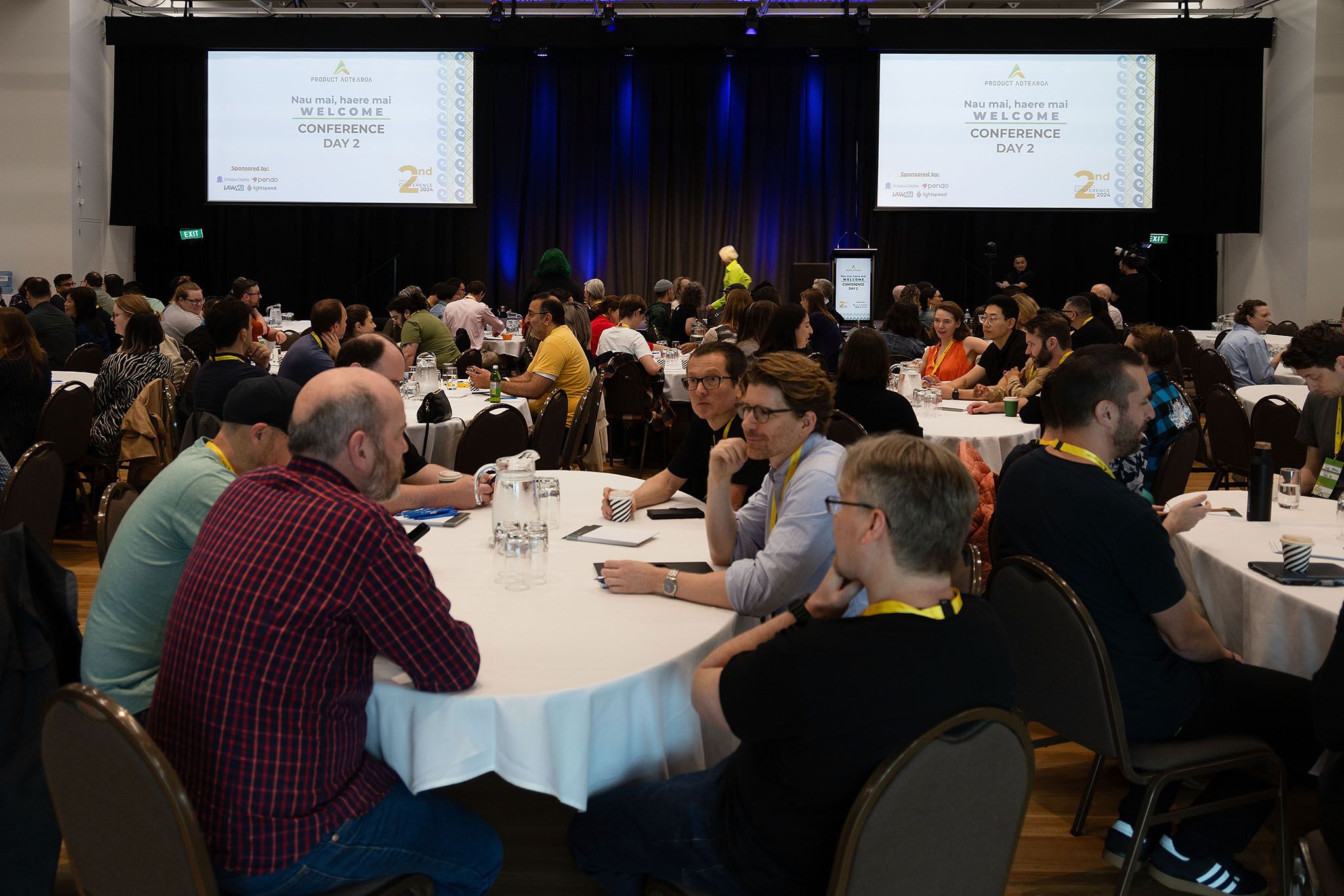 Product professionals gathered around tables at a past Product Aotearoa conference
